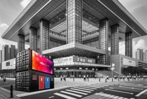 Mobiler MEDIA-Container mit großem MEGA SCREEN LED Display vor einem modernen Messegebäude